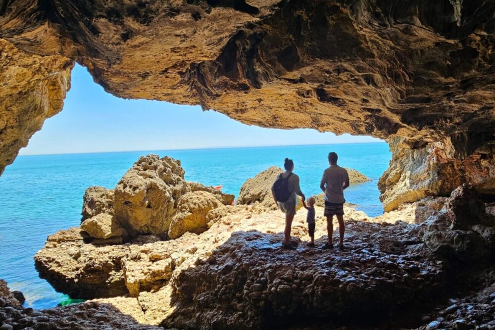 Emerging from a dark cave into sunlight and water, symbolizing personal growth, overcoming self-doubt, and embracing confidence—featuring a couple with their toddler