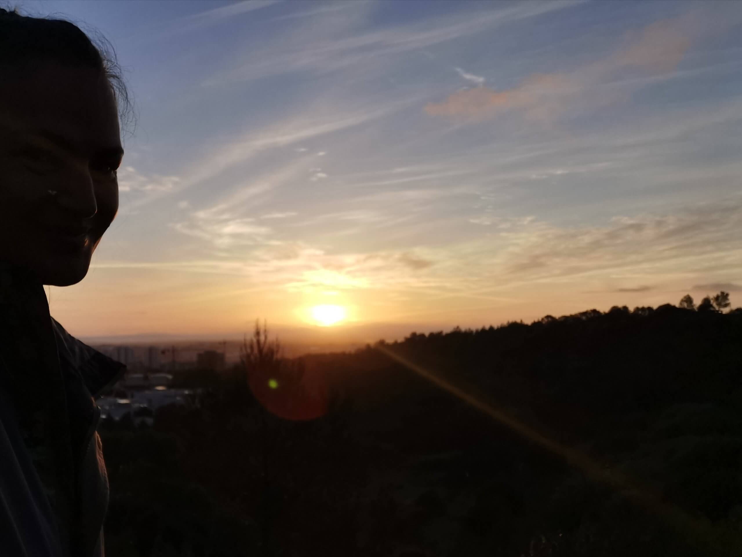 Partial silhouette of a woman watching the sunrise over hills — symbolising cognitive reframing, emotional clarity, and rising into leadership with the 1% Happier Me Today method.