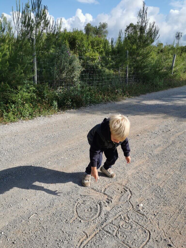 Toddler drawing a tractor sketch in the middle of a quiet nature path, focused and fully immersed — a moment of finding flow with kids